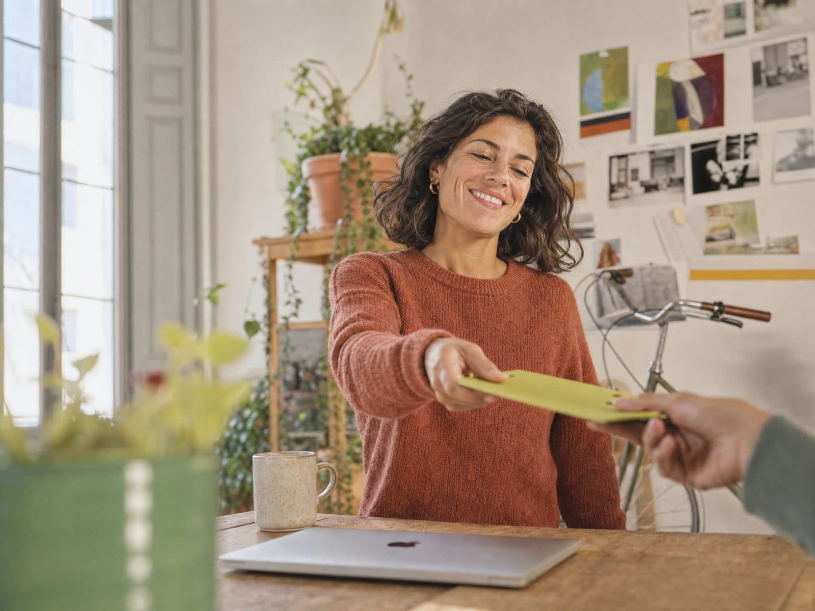 Una autónoma entrega un sobre verde desde su mesa